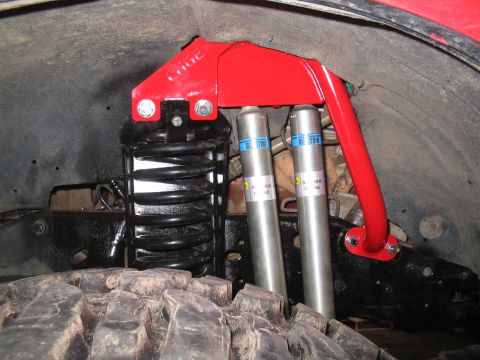 1989 Ford Bronco - Close-up of aftermarket suspension parts, including Bilstein shocks and a red support bracket.