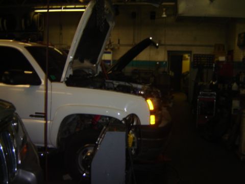 1992 Ford Bronco - White pickup truck in a garage with its hood open, undergoing service.
