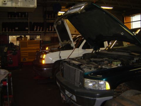 1992 Ford Bronco - Two trucks are in a garage with their hoods open, appearing to be undergoing maintenance.