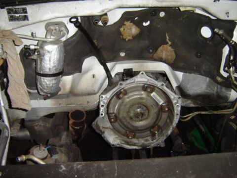 1992 Ford Bronco - Close-up of the transmission and AC system components in a vehicle's engine bay.