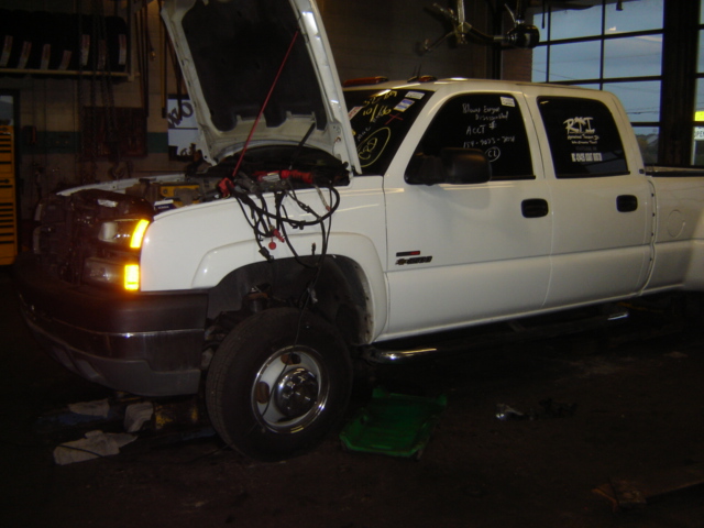 White pickup truck with hood open, wires exposed, and text on windows