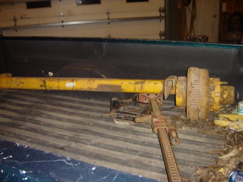 1992 Ford Bronco - Yellow axle assembly and jack are stored in the bed of a pickup truck.