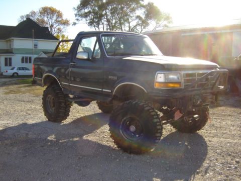 1992 Ford Bronco - This lifted Ford Bronco is shown in a three-quarter front view, parked outdoors on a sunny day.