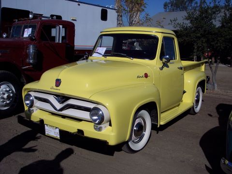 1981 Kenworth W900A - A yellow 1953 Ford F-series pickup truck is parked next to a maroon truck.
