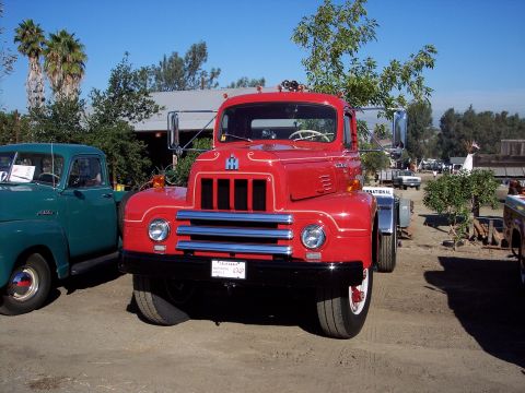 1981 Kenworth W900A - A classic red International truck is displayed outdoors, with another vintage truck visible to its left.