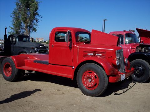 1981 Kenworth W900A - A red COE truck is parked outdoors with its hood open, alongside other trucks.