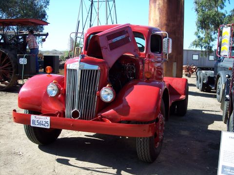 1981 Kenworth W900A - A red truck is parked outdoors with its hood open, showing the engine. Another truck is visible to the right.