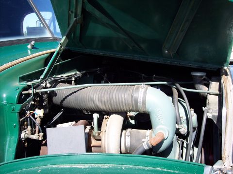 1981 Kenworth W900A - The open hood reveals the engine compartment of a green truck, showing various hoses and mechanical components.