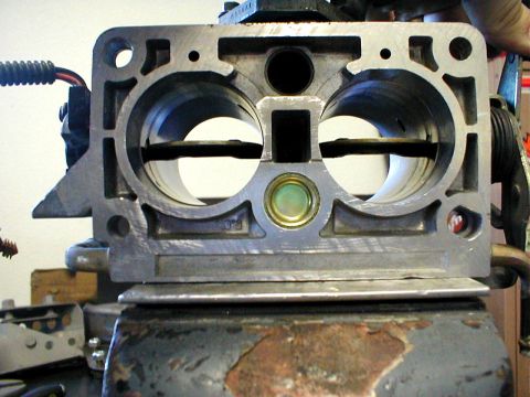 1996 Ford Bronco - A metal throttle body, likely from an engine, is clamped in a vise.