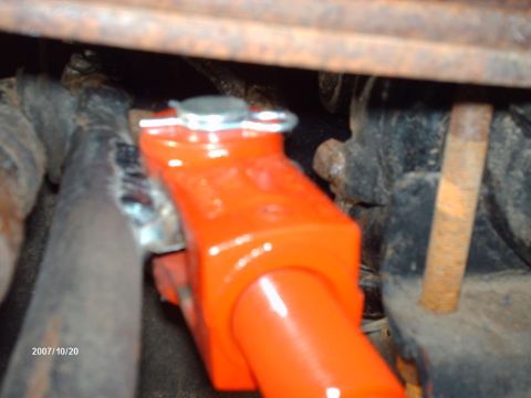 1990 Ford F-150 - A close-up view of a bright orange vehicle suspension component, likely part of an axle modification.