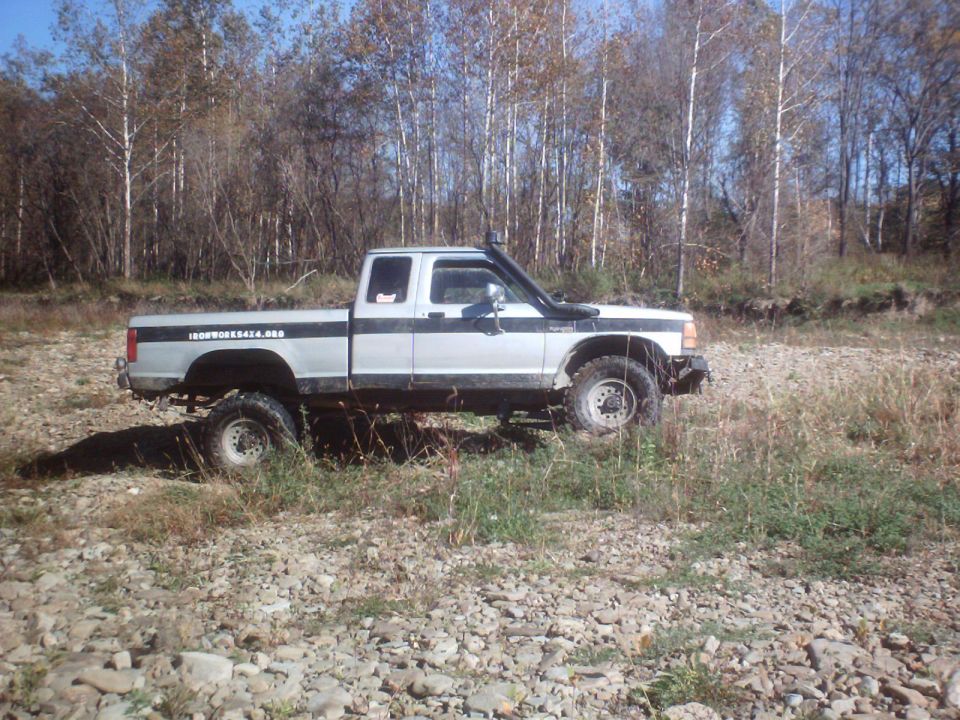 Lifted pickup truck with snorkel parked on rocky ground near trees