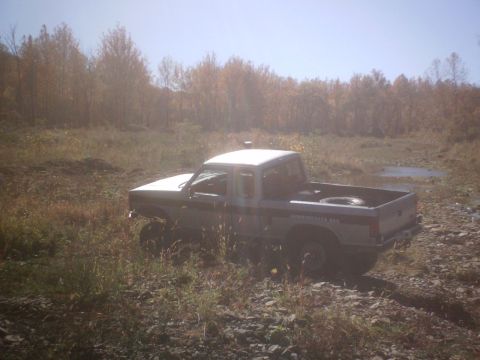 1990 Ford Ranger - A lifted 1990 Ford Ranger navigates a rough, grassy terrain during autumn.