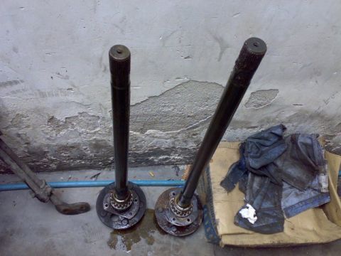 1995 Ford F-150 - Two axle shafts are shown resting on a concrete floor next to some rags and cardboard.