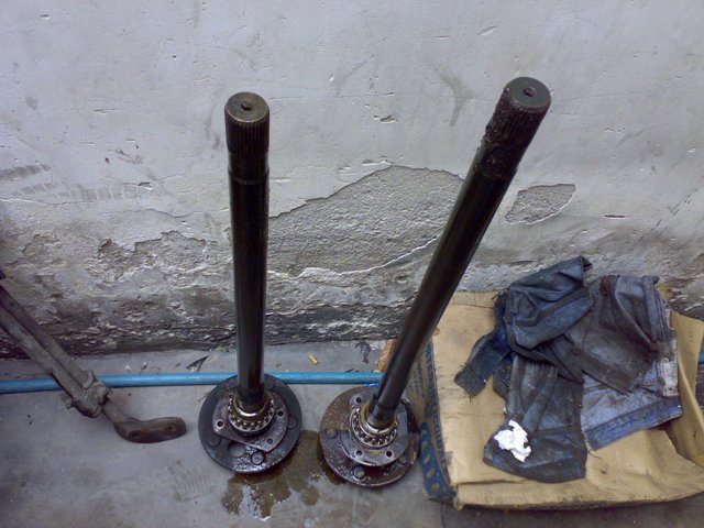 Two axle shafts with bearings and flanges on a concrete floor