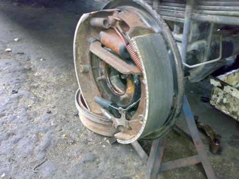 1995 Ford F-150 - Close-up view of a rusty rear axle brake drum assembly, showing the brake shoes and springs.
