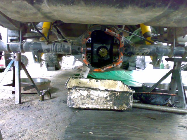 Underside of a vehicle on jack stands, showing the rear axle differential with the cover removed