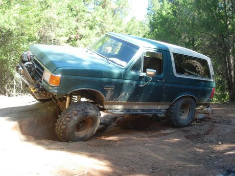 1995 Ford Bronco - This 1995 Ford Bronco is shown off-roading on a dirt trail with large rocks.