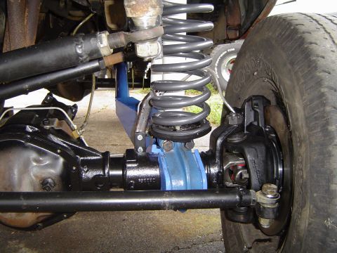 1978 Ford Bronco - Close-up view of a vehicle's front suspension and differential, highlighting blue aftermarket components and a coil spring.