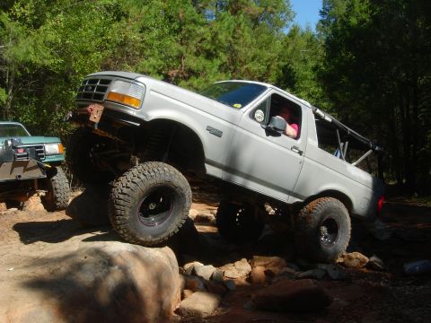 1995 Ford Bronco - Modified 1995 Ford Bronco navigates a rocky off-road course with another vehicle in the background.