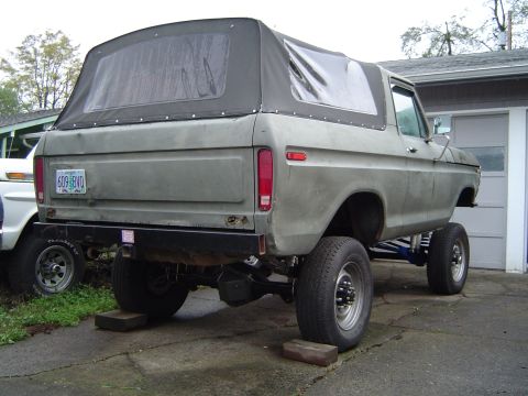 1978 Ford Bronco - Rear view of a lifted 1978 Ford Bronco with a soft top, parked next to another vehicle.