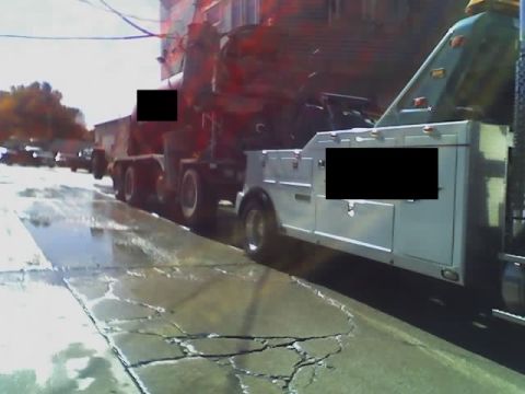 1992 Ford Bronco - A tow truck is seen towing a cement mixer on a wet, cracked street.