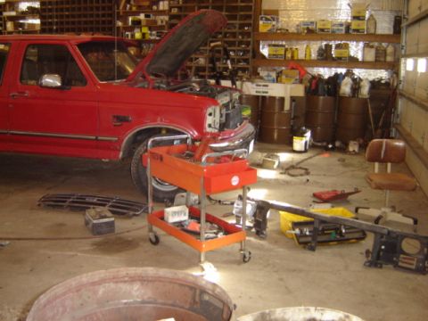 1992 Ford Bronco - Red 1992 Ford Bronco in a workshop, undergoing maintenance with its hood up.