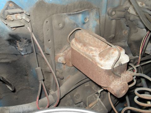 1979 Chevrolet C/K Pickup - Close-up of a rusty master cylinder and associated brake lines, mounted on the firewall of a blue vehicle.