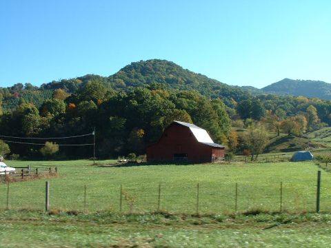 1995 Ford Bronco - A scenic view of a red barn and rolling hills in a rural setting.