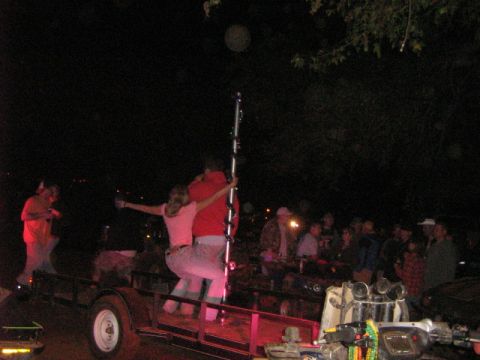 1986 Ford Bronco - A group of people are gathered around a trailer at night, with some individuals interacting with a pole on the trailer.