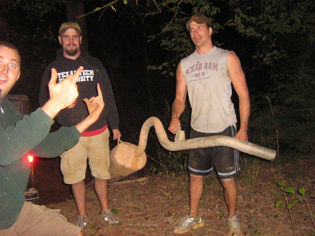 three guys holding a large exhaust pipe