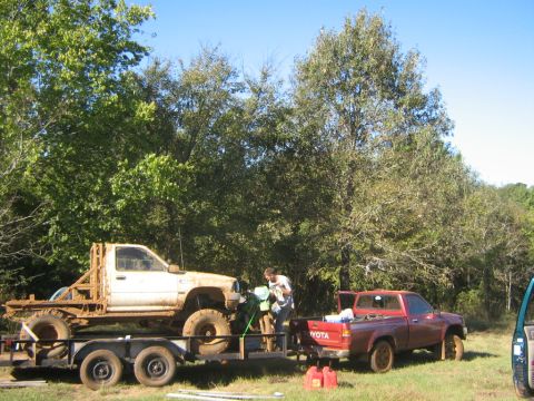 1986 Ford Bronco - Two Toyota pickups are parked outdoors with a dirt bike being loaded onto a trailer.