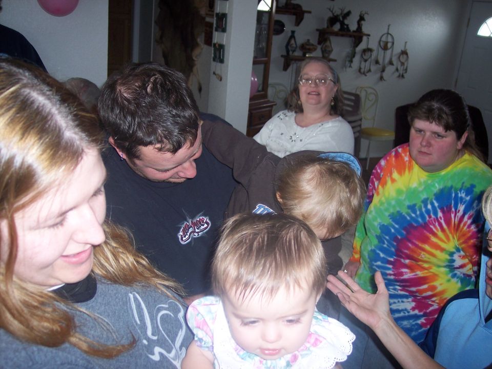 People gathered indoors, with a baby in the foreground and adults behind