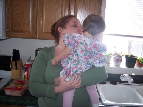 1972 Ford Ranchero - A woman holds a baby in a kitchen setting near a sink and window.