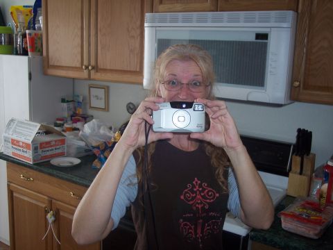 1972 Ford Ranchero - A woman poses for a photo while holding a camera in a kitchen setting.
