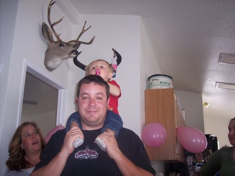 1972 Ford Ranchero - A man carries a child on his shoulders while a woman looks on, with a mounted deer head and balloons in the background.