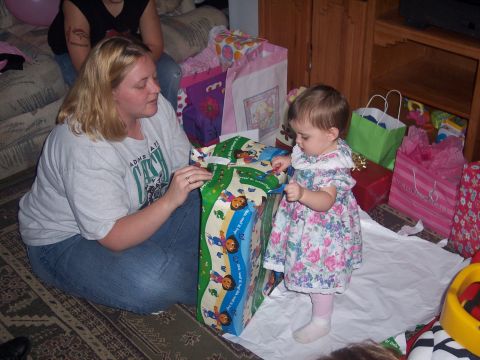 1972 Ford Ranchero - A woman and a baby girl are opening a large gift at a birthday party surrounded by many wrapped presents.