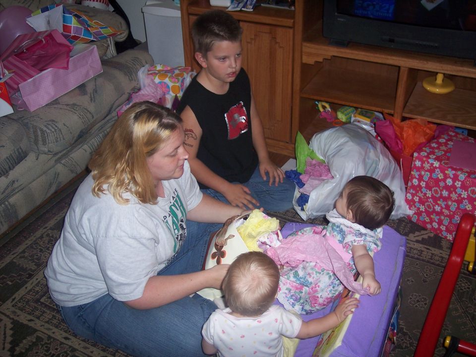 Woman and two kids sit on floor with gifts and toys around them