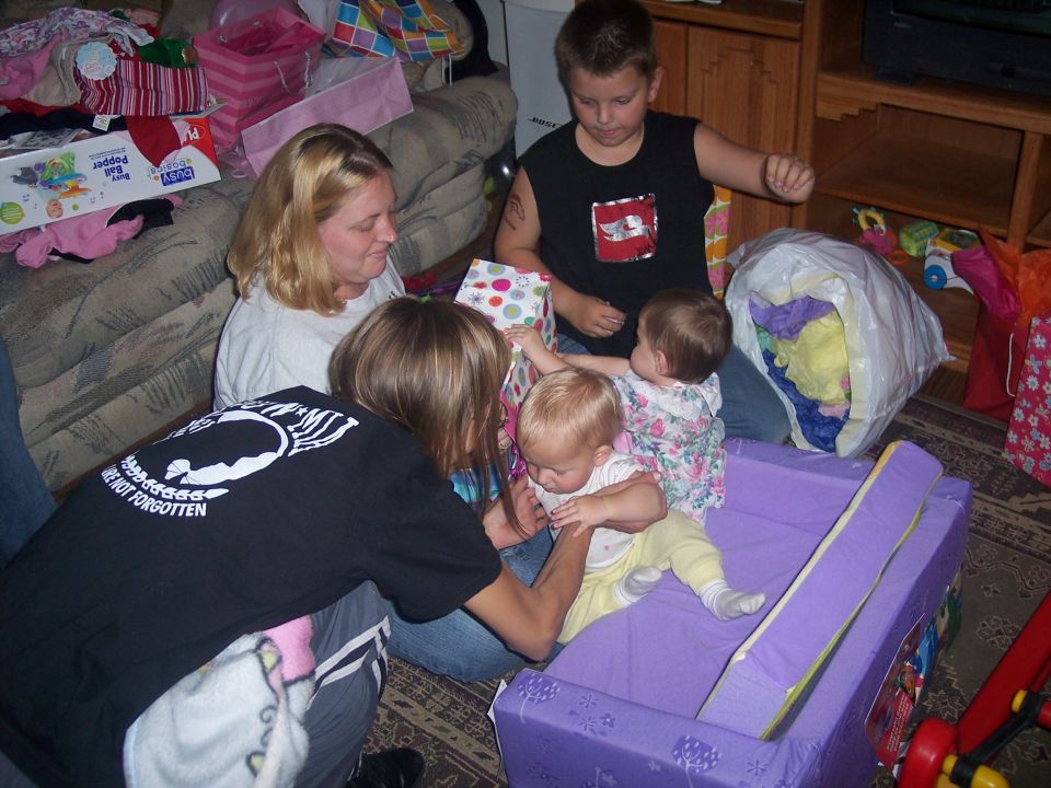 Family gathered around opening gifts, with children and adults present