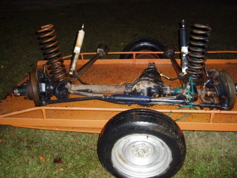 1980 Ford Bronco - Dana 44 front axle assembly with shocks and springs is shown on a trailer.