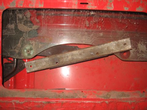 1979 Ford Bronco - Interior view of a red tailgate, revealing the window regulator mechanism and a metal track. This part is consistent with a 1979 Ford Bronc…