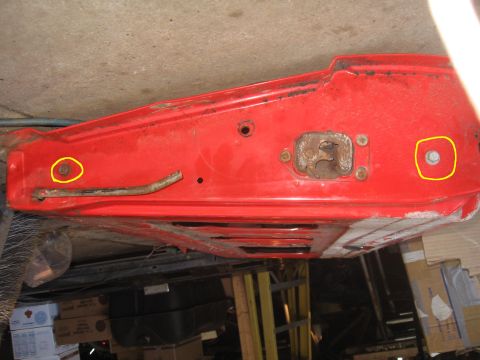 1979 Ford Bronco - Close-up of a red car door's interior showing the latch mechanism and mounting hardware.