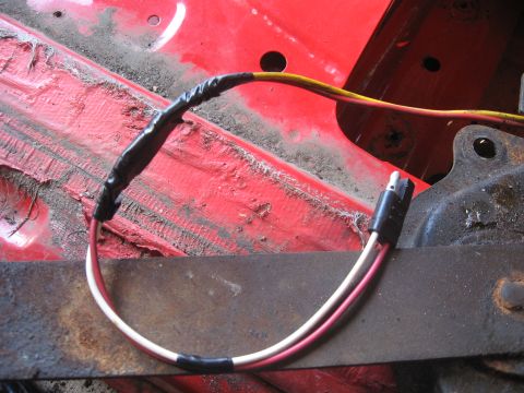 1979 Ford Bronco - Close-up of a vehicle's wiring harness, showing electrical connections and red painted metal.