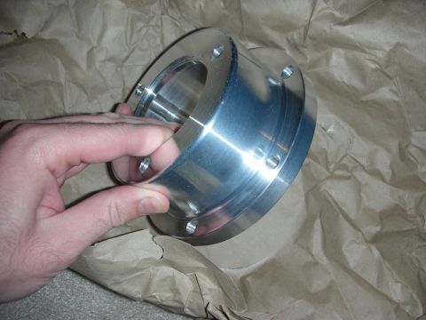 1998 Ford Crown Victoria - hand holds a cylindrical polished aluminum bearing/housing component above brown packing paper.