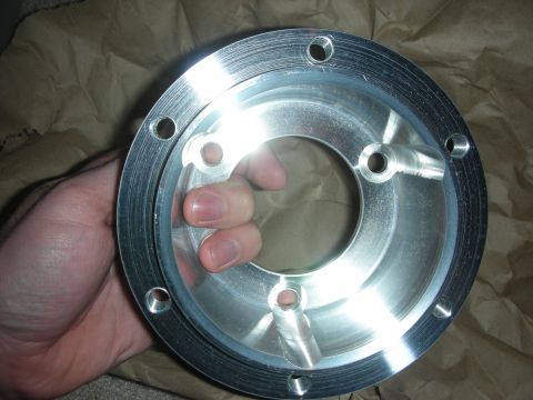 1998 Ford Crown Victoria - Close-up of a hand gripping a circular machined aluminum flange plate with multiple bolt holes and a center bore.