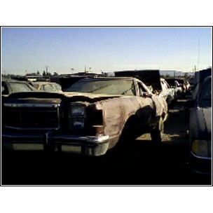 1972 Ford Ranchero - A weathered vehicle sits in a junkyard under a clear sky, with other cars visible in the background.