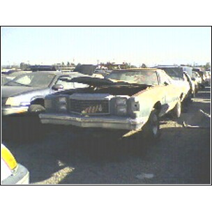 1972 Ford Ranchero - A weathered vehicle sits in a junkyard with its hood up, surrounded by other cars.