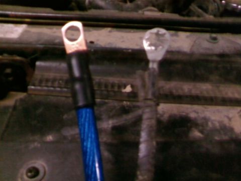 1995 Ford Bronco - Close-up of battery cables, one blue with a copper terminal and the other gray and frayed.
