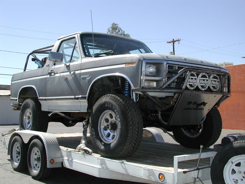 1980 Ford Bronco with custom bumper and roll cage, loaded on a trailer