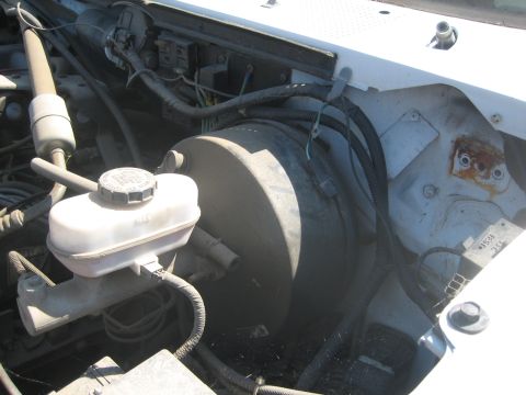 1995 Ford Bronco - Engine-bay view of the driver's-side firewall area showing a translucent brake master cylinder reservoir with MAX fill marking and its roun…
