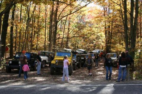 1992 Jeep Cherokee - A collection of Jeeps are parked on a dirt road surrounded by trees in autumn colors.